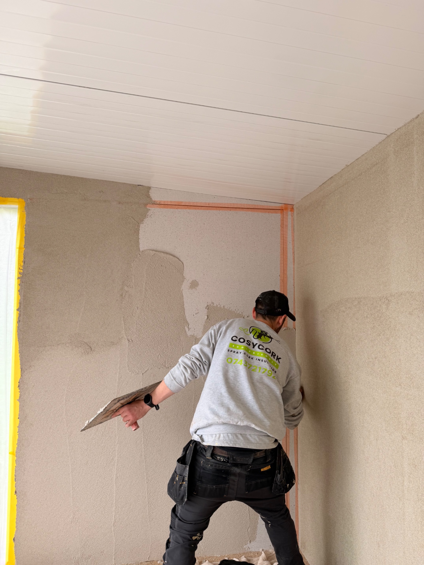 CosyCork worker applying cork insulation to an internal wall with a trowel